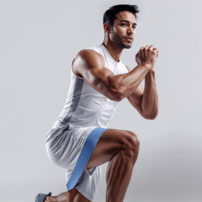 Man performing a squat exercise with a resistance band on a plain background